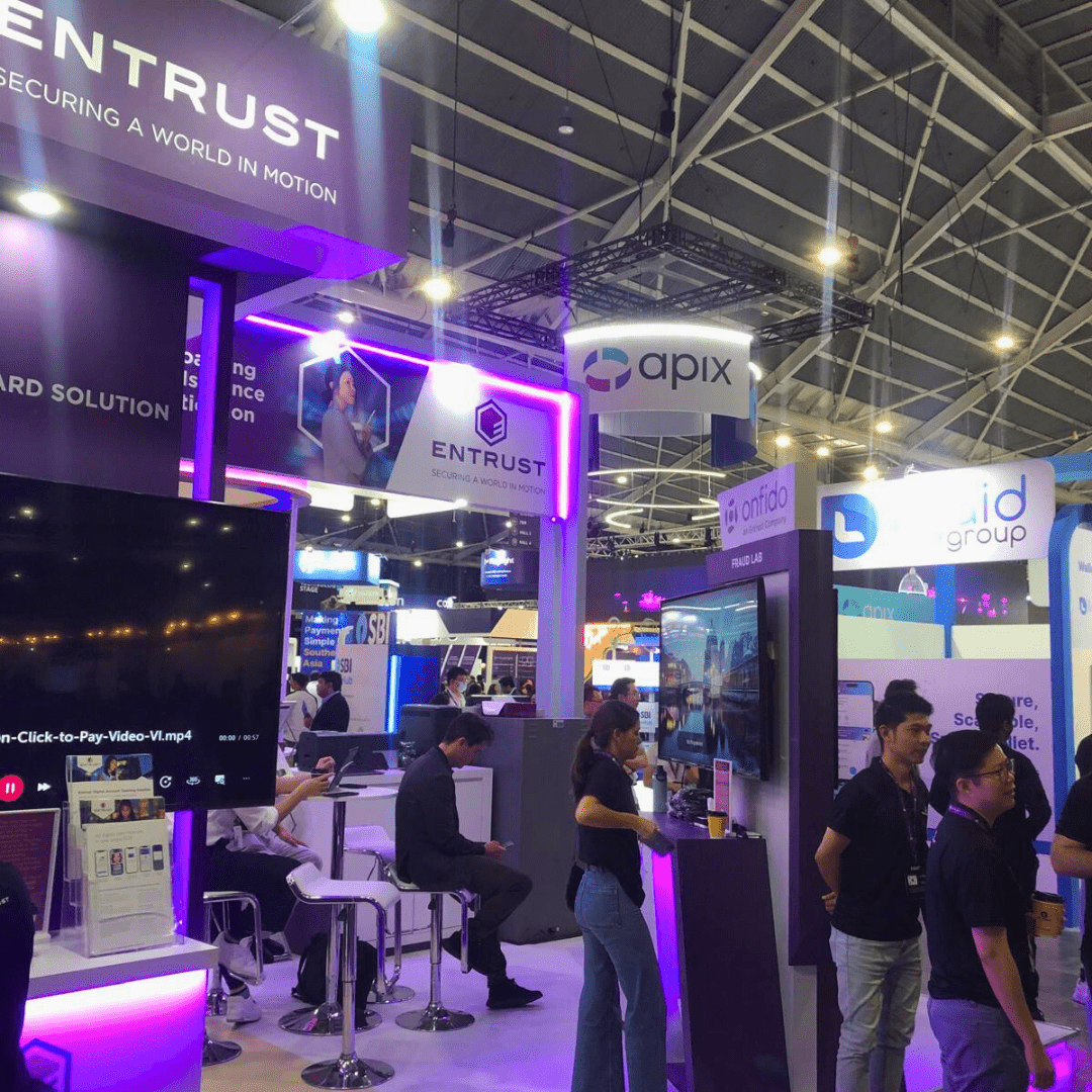 Entrust booth showcasing its security solutions at a fintech exhibition, with people engaging and standing nearby other notable booths like Apix and Onfido.