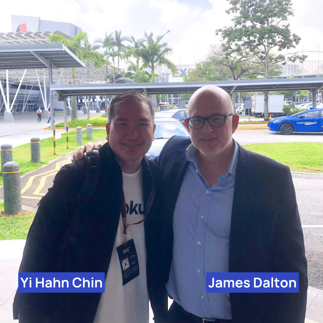 James Dalton standing with Yi Hahn Chin, smiling outdoors at a fintech event in Singapore with the event venue in the background.